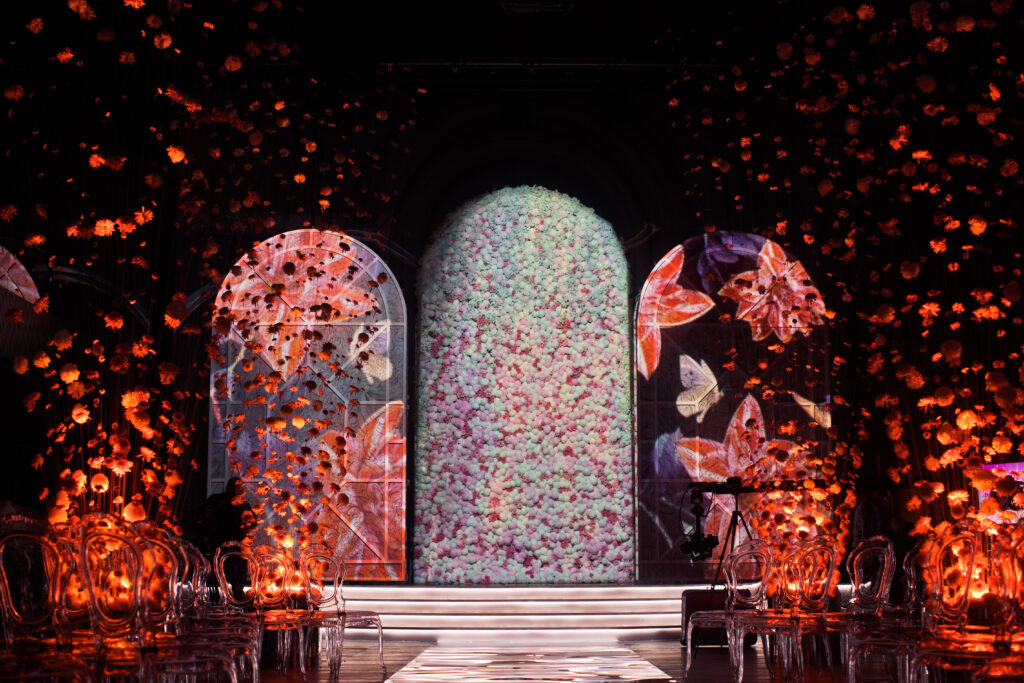 glance path leads to bright archs with flowers in dark room